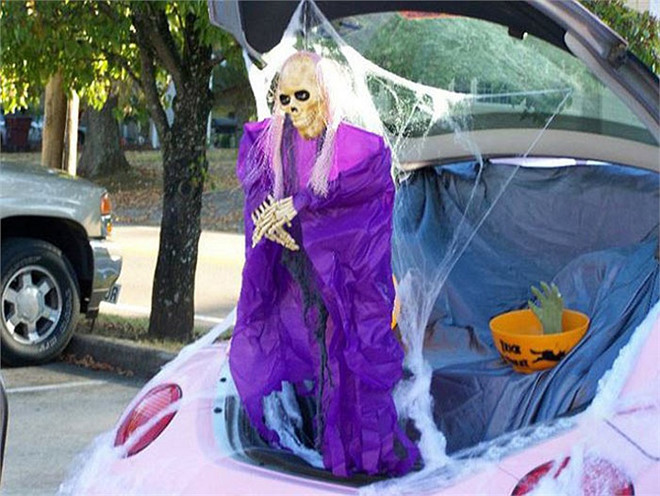 Chiếc xe màu hồng nữ tính đối lập với hình ảnh kinh dị của bộ xương khô đứng phía sau cốp xe.