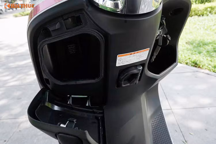 Phía trước chỗ ngồi của người lái là nơi đặt các hộc để đồ nhỏ. Hộc bên trái có hỗ trợ ổ sạc điện thoại 12V. Ở bên phải là nơi đặt ổ khóa (đáng tiếc nó không được trang bị chìa khoá smartkey), nút bấm mở yên và một hộc nhỏ để đồ phía dưới. Ở giữa cũng có một móc treo đồ dùng.