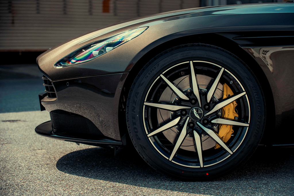 Nổi bật ở ngoại thất xe Aston Martin DB11 Kopi Bronze là bộ mâm thể thao đa chấu 2 tone màu có kích thước 20 inch. Xe trang bị kẹp phanh màu vàng tương phản cùng đĩa phanh làm từ chất liệu gốm carbon.