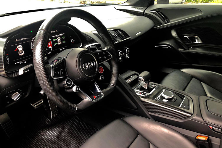 Bên trong, nội thất Audi R8 V10 Plus nổi bật với chất liệu da bọc cao cấp đi kèm kim loại và carbon siêu nhẹ. Vô-lăng thể thao 3 chấu tích hợp nhiều phím chức năng cơ bản cũng như công nghệ hỗ trợ người lái, phía sau là màn hình hiển thị thông tin chi tiết các thông số kĩ thuật của xe.