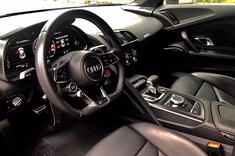 Bên trong, nội thất Audi R8 V10 Plus nổi bật với chất liệu da bọc cao cấp đi kèm kim loại và carbon siêu nhẹ. Vô-lăng thể thao 3 chấu tích hợp nhiều phím chức năng cơ bản cũng như công nghệ hỗ trợ người lái, phía sau là màn hình hiển thị thông tin chi tiết các thông số kĩ thuật của xe.