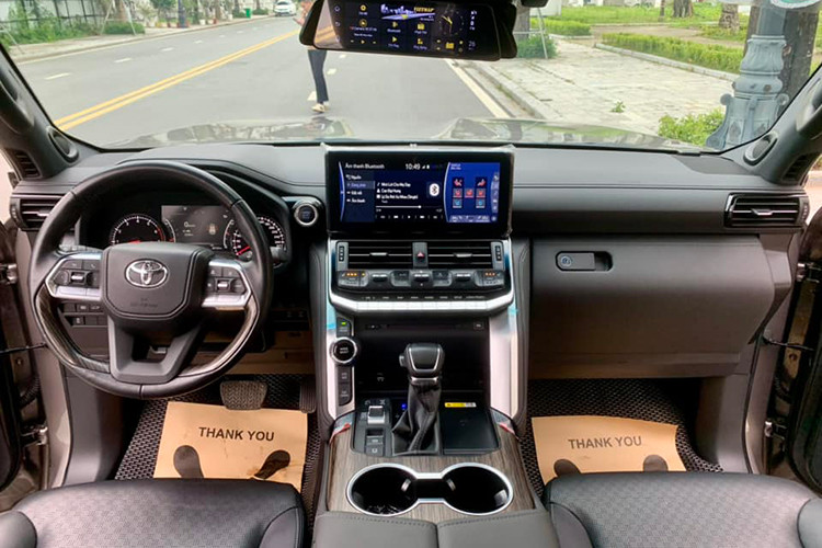 Khoang nội thất xe có màu tối chủ đạo, đã xuất hiện dấu hiệu của thời gian với độ ngả màu nhẹ và không còn căng bóng. Các trang bị nổi bật bên trong của Land Cruiser đời 2022 có thể kể đến như màn hình 12,3 inch, hỗ trợ kết nối Apple CarPlay/Android Auto...