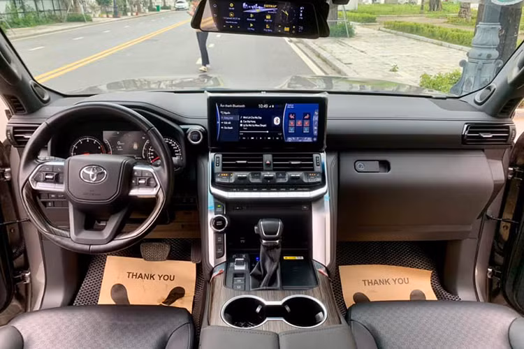 Khoang nội thất xe có màu tối chủ đạo, đã xuất hiện dấu hiệu của thời gian với độ ngả màu nhẹ và không còn căng bóng. Các trang bị nổi bật bên trong của Land Cruiser đời 2022 có thể kể đến như màn hình 12,3 inch, hỗ trợ kết nối Apple CarPlay/Android Auto...