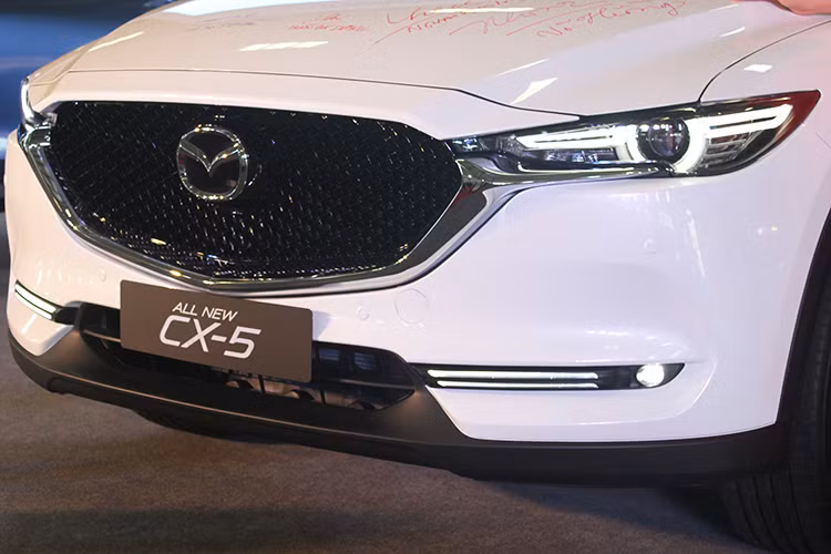 Ở thế hệ mới, Mazda CX-5 2018 tạo ấn tượng với lưới tản nhiệt được mở rộng bằng họa tiết 3D hiện đại, kết hợp với đường viền kim loại sáng, sắc nét thay cho bộ lưới tản nhiệt bằng thanh ngang ở các thế hệ trước. Bên dưới là hốc gió kéo dài theo chiều ngang và khá hẹp khiến đầu xe rộng và trở nên sang trọng, lịch lãm hơn so với trước đây.