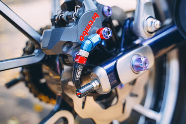 Để liên kết đĩa &amp; heo cố định hoàn chỉnh trên bánh lái trước bắt buôc phải gia công pas nhôm CNC chạy máy cho độ chính xác cực cao, pas được nhuộm đen để mang lại sự cứng cáp cho người nhìn. Bên cạnh đó là dây dầu Earl's UK nổi bật với gam màu đỏ, toàn bộ chi tiết ở bánh lái trước được cố định bằng ốc Proti cấu tạo từ Titanium.