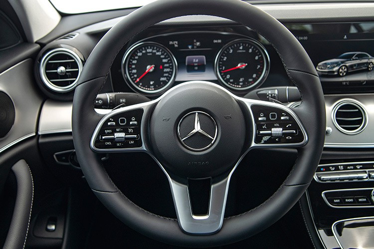 Vô-lăng trên Mercedes-Benz E180 được bọc da Nappa, mang đến cảm giác cầm rất mềm mại, được điều chỉnh điện 4 hướng tích hợp lẫy chuyển số phía sau. Giống như "đàn anh" là phiên bản E 200 2019, cụm đồng hồ trên phiên bản E180 cũng dừng lại ở dạng ống truyền thống với màn hình màu hiện thị thông tin ở chính giữa. Nếu khách hàng muốn bảng đồng hồ kỹ thuật số có thể tuỳ biến giao diện, E200 Exclusive sẽ là sự lựa chọn.