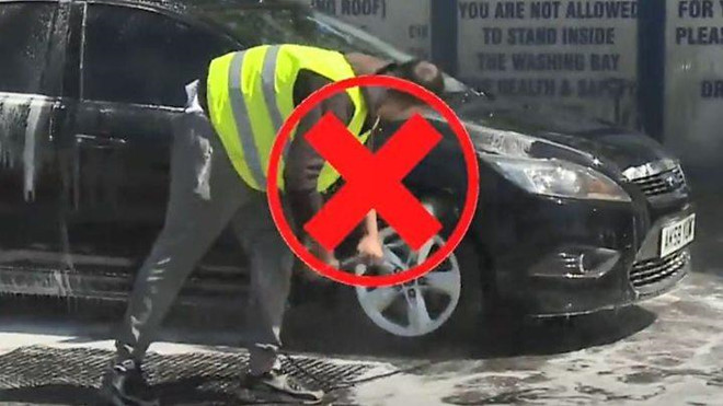 Lính cứu hỏa phải phun dung dịch chống cháy vào một chiếc sedan đang tan chảy tại Anh. Ảnh: bbc.