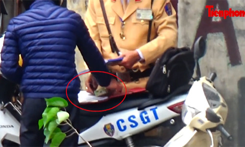 Cảnh sát giao thông Hà Nội nhận một tờ nghi là tiền từ một người vi phạm giao thông - Ảnh cắt từ clip