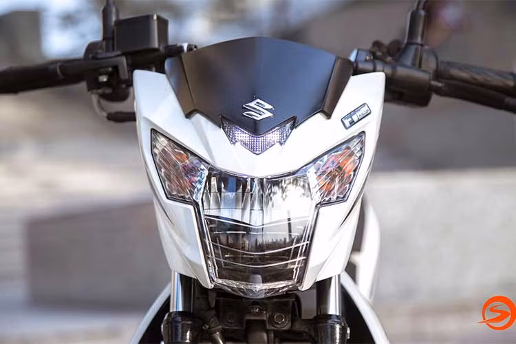 So với phiên bản tiền nhiệm, Raider R150 Fi sở hữu một vẻ ngoài ấn tượng hơn nhiều. Phần đầu xe nổi bật với cụm đèn pha lớn dạng chữ T, cùng cặp đèn xi nhan dạng giọt nước nằm tách biệt đối xứng hai bên. Bên cạnh đó, phần chính giữa đầu xe còn đính logo chữ S đặc trưng của hãng.