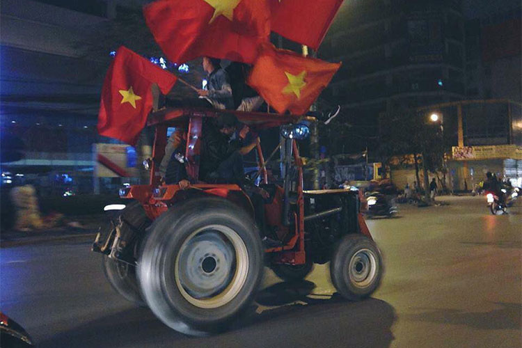 Một chiếc máy cày chỏ khá đông cổ động viên với cờ đỏ sao vàng.