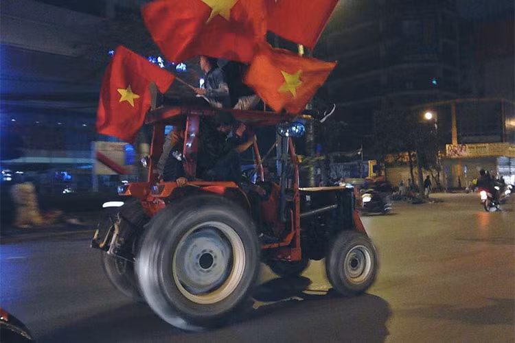 Một chiếc máy cày chỏ khá đông cổ động viên với cờ đỏ sao vàng.