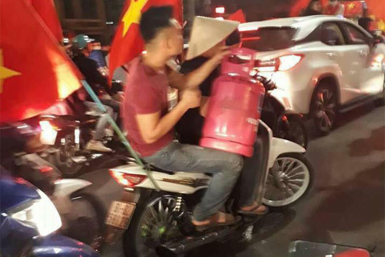 Những thanh niên quá khích còn cưỡi cả xe máy, mang theo bất kỳ vật dụng gì có thể phát ra âm thanh, thậm chí là lửa... Trong ảnh là một thanh niên đi xe máy đầu trần ôm bình ga xuống đường được xem là hình ảnh không đẹp, thậm chi xấu xí và gây nguy hiểm đến tính mạng.