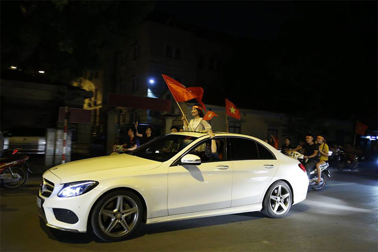 Một chiếc xe sang Mercedes-Benz được chủ nhân mở mui vẫy cờ đỏ sao vàng ủng hộ đội tuyển Olympic Việt Nam sau chiến thắng lịch sử.