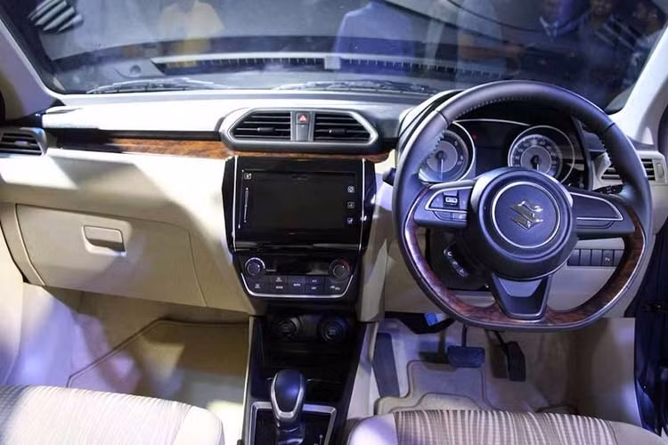 Bên cạnh đó, bảng táp-lô của xe cũng được thiết kế với các đường kẻ ngang và hệ thống giải trí thông tin nổi. Vô-lăng 3 chấu được kế thừa từ mẫu Swift mới, hai ghế trước được thiết kế với hai tông màu be và màu nâu. Ngoài ra, các trang bị nổi bật khác có thể kể đến như cổng sạc 12V cho ghế trước/sau, đầu cắm USB và audio, 4 loa và cảm biến lùi.