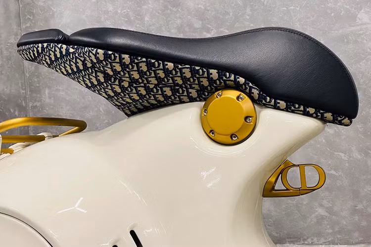 Điểm khác biệt dễ dàng nhận thấy nhất và cũng ấn tượng nhất trên Vespa 946 Christian Dior đến từ màu sơn và các phụ kiện đi kèm. Chiếc xe được khoác trên mình lớp “áo” màu trắng nhẹ nhàng kết hợp với các điểm nhấn màu vàng đồng và họa tiết trang trí đặc trưng của thương hiệu thời trang Pháp.