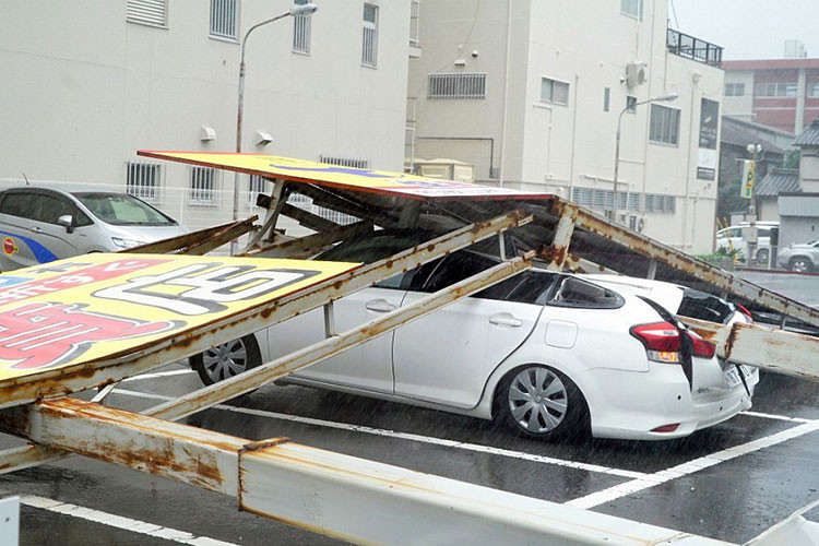 Những tấm pa nô, áp phích đè nát một chiếc sedan tại bãi đỗ.