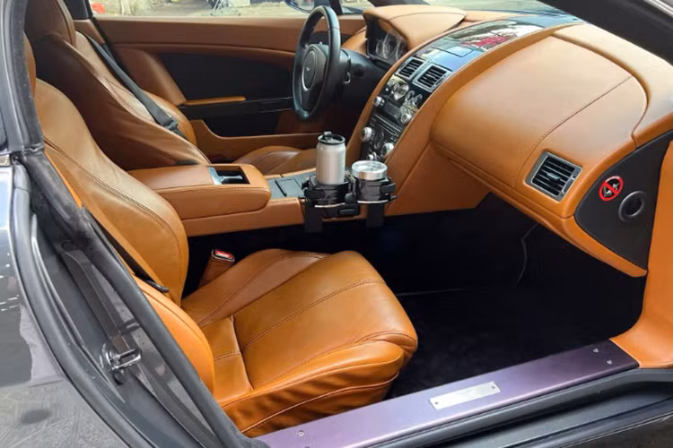 Phần da ghế của Aston Martin Vantage V8 Roadster đời 2009 này dù đã xuất hiện các vết nhăn do dấu ấn của thời gian nhưng không quá đáng kể. Xe cũng được trang bị khay đựng cốc và gạt tàn mang đậm phong cách của “vua cafe”.