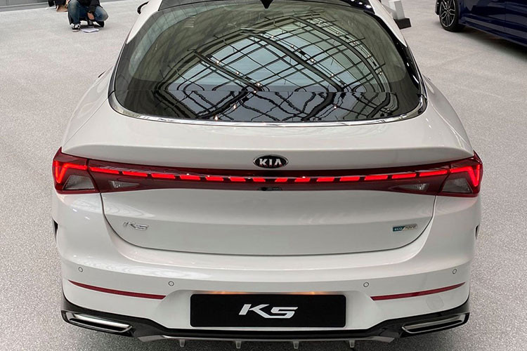 Đầu xe K5 All New vẫn trung thành với lưới tản nhiệt hình mũi hổ, song đã có tạo hình tràn viền đầy mới mẻ với dạng vân sóng bắt mắt. Nối liền lưới tản nhiệt là cặp đèn pha LED với 3 bóng xếp xếp tầng mới. Ấn tượng nhất phải kể đến phần đuôi xe với dải đèn LED đứt chạy ngang khoang hành lý mô phỏng thiết kế của những chiếc xe hạng sang nối liền đèn hậu mang đến vẻ thống nhất cho khu vực này.