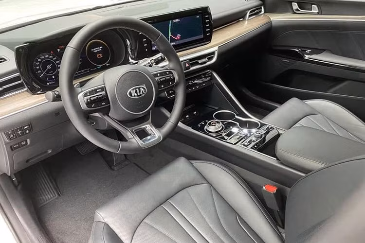 Bước vào khoang nội thất, Kia K5 2021 hướng thiết kế tập trung vào người lái nhiều hơn. Vô-lăng xe bọc da kết hợp đầy đủ phím chức năng, lẫy chuyển số được tích hợp đồng nghĩa với việc K5 mới được trang bị tính năng lái thể thao, phía sau là màn hình đồng hồ điện tử hoàn toàn.