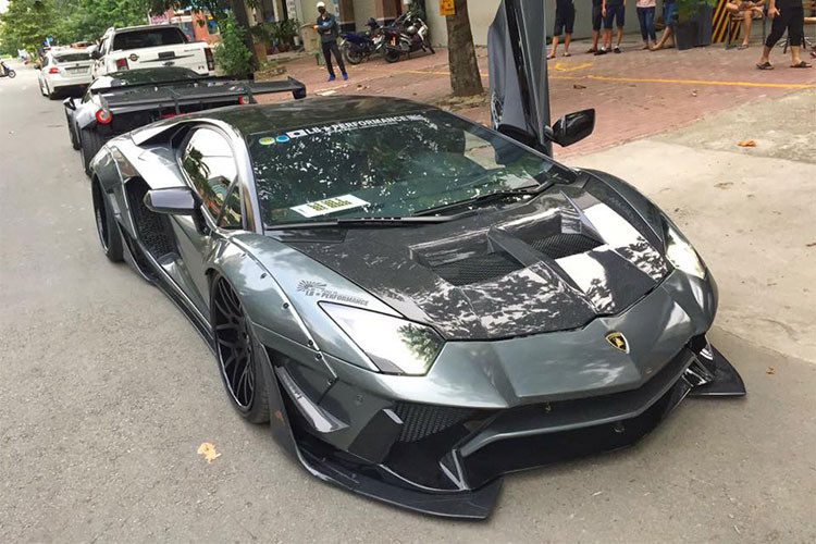 Cánh lướt gió mới với kích thước "khủng" ở đầu, bên hông và đuôi xe bằng sợi carbon cũng mang đến diện mạo hiếu chiến hơn cho siêu xe độ Lamborghini Aventador Limited Edition 50 của Liberty Walk. Tông màu chủ đạo của bản độ siêu xe này là xám phối cùng sợi carbon bóng.