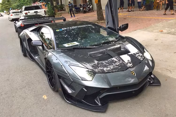 Cánh lướt gió mới với kích thước "khủng" ở đầu, bên hông và đuôi xe bằng sợi carbon cũng mang đến diện mạo hiếu chiến hơn cho siêu xe độ Lamborghini Aventador Limited Edition 50 của Liberty Walk. Tông màu chủ đạo của bản độ siêu xe này là xám phối cùng sợi carbon bóng.