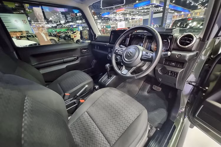 Tay nắm cửa sơn cùng màu thân xe Suzuki Jimny 2023, ốp cua lốp nổi bật, vành hợp kim 15 inch cũng như lốp 195/80R15. Riêng chiếc Suzuki Jimny 2023 màu xanh Solid Jungle Green trong triển lãm BIMS 2023 có thêm một số trang bị như lốp A/T có kích thước 235/75R15, thang leo lên nóc và móc kéo phía sau.