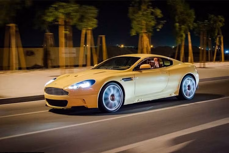 Một chiếc Aston Martin DB9 đắt tiền lướt trên đường phố trong đêm.