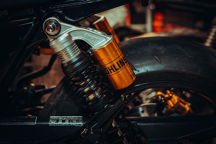 Nhìn từ phía sau, phần đuôi xe đã được cắt ngắn. Những chi tiết dè sau, đèn hậu, đèn xin nhan nguyên bản được người thợ khéo léo thay thế bằng cụm đèn “đồ chơi” gắn vào trong khuôn sườn, tích hợp đầy đủ đèn hậu, đèn xi nhan. Bên cạnh đó, các chi tiết như phuộc trước của xe thay thế bằng phuộc Up Side Down thương hiệu showa của chiếc Suzuki GSX, phuộc sau Ohlins phụ tùng chuyên biệt cho CB400SF.