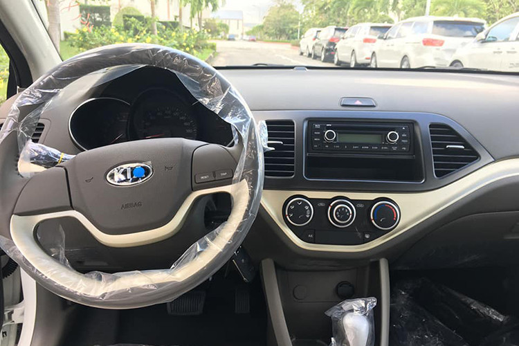 Bên trong xe, khu vực cần số là khác biệt lớn nhất với Morning EX MT. Vô lăng 2 chấu đơn giản với 2 nút bấm điều chỉnh thông số trên đồng hồ. Kia Morning AT mới cũng giống bản giá rẻ, không có màn hình trung tâm, chỉ có radio và các núm chỉnh điều hòa.