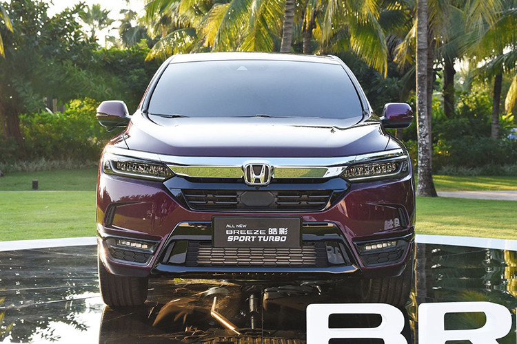 Được áp dụng ngôn ngữ thiết kế Solid Wing Face, Honda Breeze 2020 có thanh mạ crôm dày dặn trên lưới tản nhiệt nối liền với cụm đèn pha thanh mảnh. Bên trong cụm đèn pha này là các bóng đèn có thiết kế như đá quý khá ấn tượng. Bên dưới là hốc gió màu đen và đèn sương mù hình tròn. Chưa hết, hãng Honda còn trang bị ốp màu đen kéo dài từ hốc đèn sương mù đến cản sau. Điều ngạc nhiên là Honda Breeze không hề có nẹp màu đen bao quanh hốc bánh như người anh em CR-V.