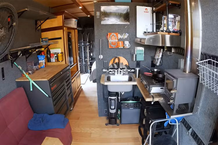 Không gian bên trong có đầy đủ công năng của một ngôi nhà. Khu vực nhà bếp có một hộp dụng cụ lớn, có thể nhân đôi không gian tủ với mặt bàn. Tủ lạnh và hệ thống điện được sắp xếp gọn gàng trong chiếc hộp tận dụng lại. Đối diện là nơi đặt bồn rửa, bếp ga đôi,...