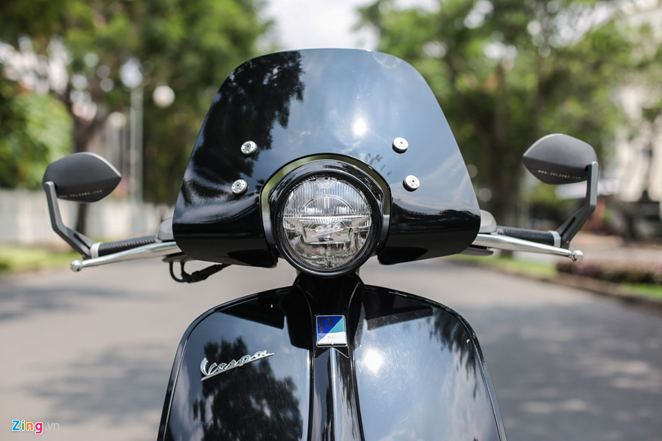 Phía trước là phần kính chắn gió dành riêng cho Vespa 946. Phần kính chắn này không đi kèm theo xe nguyên bản, chủ xe phải bỏ ra số tiền hơn 10 triệu đồng để thêm vào. Hai bên tay lái là cặp kính gù của Zelioni mang lại vẻ ngoài hiện đại, thể thao hơn.