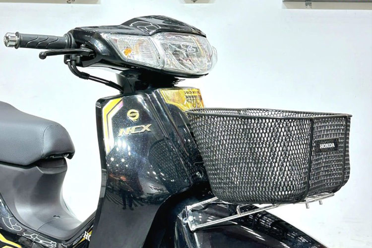 Honda Dream 125 NCX 2024 bản Campuchia sở hữu phần đầu với cụm đèn chiếu sáng và đèn hậu to bản dạng halogen, hai bên là đèn báo rẽ. Phía trước có giá gắn giỏ xe - chi tiết biến mất trên những chiếc xe máy phổ thông tại thị trường Việt Nam hiện nay.