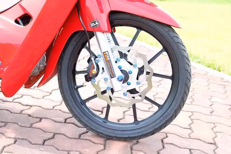 Ở phía trước, chiếc xe máy Honda Wave trong bài vẫn đi phuộc zin nhưng được hạ thấp để giảm trọng tâm và tạo dáng thể thao hơn. Đặc biệt, bộ bánh căm nguyên bản của xe đã được chủ nhân thay bằng vành Daytona của Nhật, kèm theo hệ thống phanh gồm heo Brembo Billet, đĩa Galfer 260 mm và dây dầu Spielger.