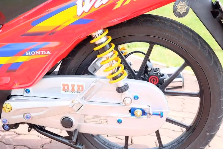 Trong khi phuộc trước được giữ nguyên bản thì ở phía sau, chiếc xe số phổ thông Honda Wave màu đỏ cờ này đã được nâng cấp lên cặp phuộc Ohlins. Hệ thống phanh sau cũng được nâng cấp lên phanh đĩa với heo Brembo Billet, kèm lốp Dunlop và dàn ốc kiểng nổi bật.