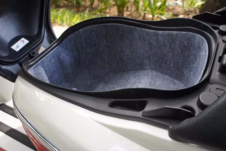 Phía dưới yên trước là hộc chứa đồ lớn được trải thảm có đèn chiếu sáng, để vừa 3 mũ bảo hiểm nửa đầu cùng một số vật dụng cá nhân...