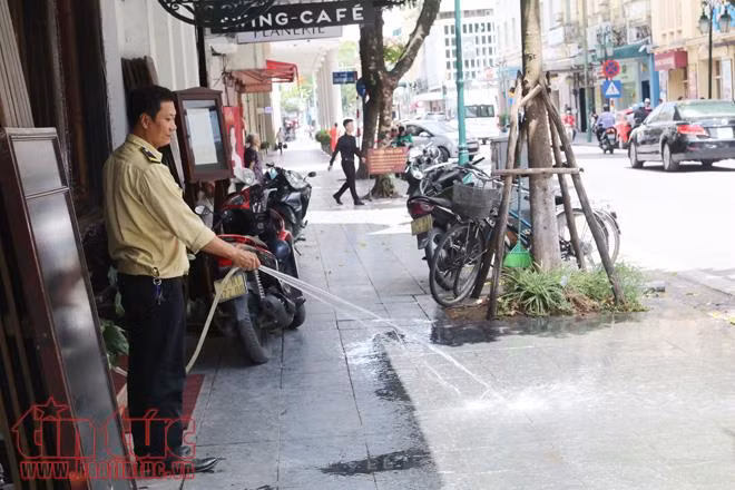 Bảo vệ của một cửa hàng phải phun nước giảm nhiệt độ để ngăn vỉa hè hắt nắng nóng lên.