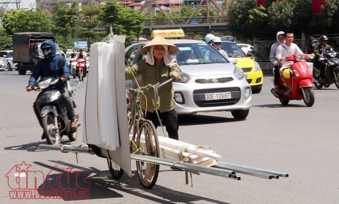 Nắng nóng, nhưng mưu sinh thì vẫn không thể "đừng" được. Đẩy xe chở phế liệu trên phố giữa trưa, chị Lan (quê Hưng Yên) than thở: "Những ngày nóng như thế này đi làm rất vất vả".