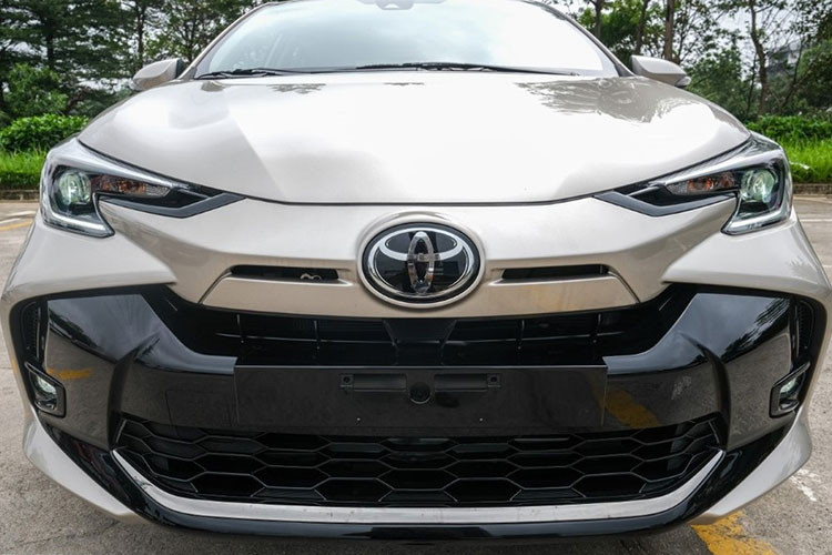 Điểm khác biệt dễ nhận ra nhất của Toyota Vios 2023 tại Việt Nam là phần đầu xe được thiết kế lại hoàn toàn. Cản trước mới hiện đại hơn với lưới tản nhiệt thất và nở rộng ra hai bên cho cảm giác trẻ trung hơn. Ngoài ra, cạnh logo Toyota có 2 khe gió nhỏ thiết kế khá giống phần đầu Corolla Cross phiên bản Nhật.