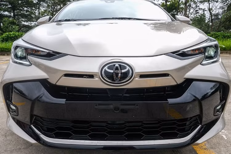 Điểm khác biệt dễ nhận ra nhất của Toyota Vios 2023 tại Việt Nam là phần đầu xe được thiết kế lại hoàn toàn. Cản trước mới hiện đại hơn với lưới tản nhiệt thất và nở rộng ra hai bên cho cảm giác trẻ trung hơn. Ngoài ra, cạnh logo Toyota có 2 khe gió nhỏ thiết kế khá giống phần đầu Corolla Cross phiên bản Nhật.