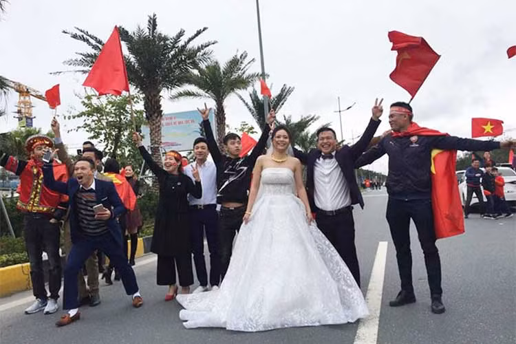 Bên cạnh cặp đôi kẹt cứng trên xe rước dâu giữa biển người thì cũng có những đôi uyên ương khác chọn đây là ngày chụp bộ ảnh cưới để đời giữ bạt ngàn cờ hoa và đặc biệt là ghi lại hình ảnh các tuyển thủ U23.