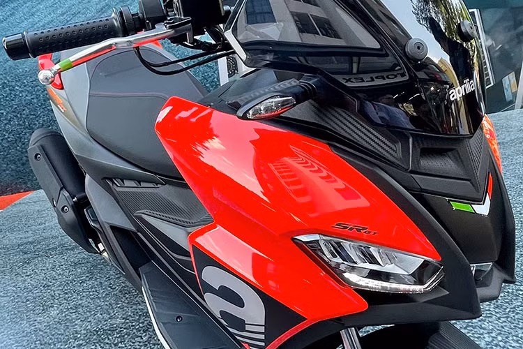 Cụm đèn chiếu sáng trước của mẫu xe tay ga thể thao nhà Aprilia được chia thành 3 ngăn riêng biệt, 2 bên là đèn chiếu gần và ở giữa là đèn chiếu xa. Phía trên được lắp kính chắn gió màu khói tương đối cao và rộng.