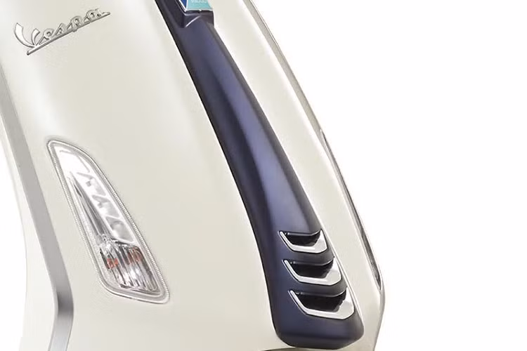 Những nét chấm phá tinh tế nổi bật trên nền trắng của bức tranh Vespa là logo “Yacht Club” dập nổi trên cốp đựng đồ phía trước, cà vạt màu xanh nhám mạ crome, đường sọc xanh đặc trưng chạy dọc thân xe.