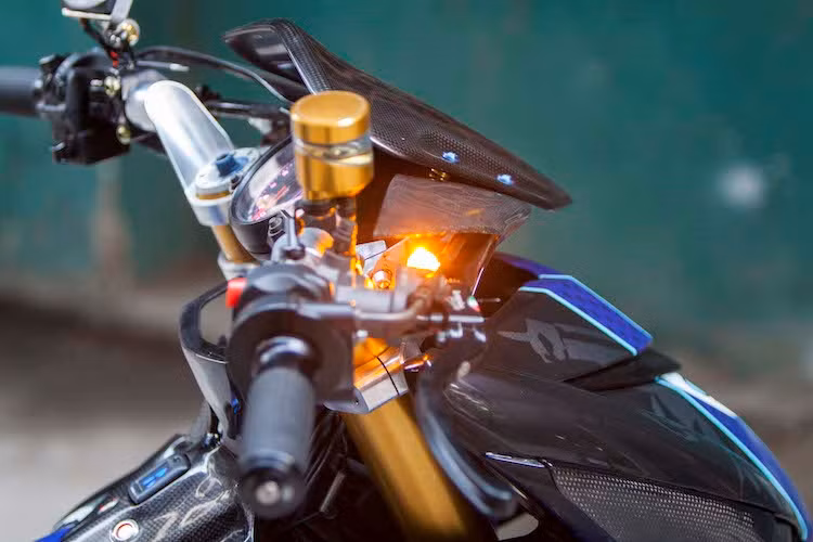 Nằm phía trên chảng ba của xe là bảng đồng hồ đa chức năng Koso RX2N, trong khi bên trên tay lái còn có thêm một đồng hồ Koso Mini 3 nhỏ. Khu vực tay lái của chiếc Exciter 150 độ khủng này cũng hội tụ nhiều món đồ chơi "hàng khủng" khác gồm cùm ga Domino, cùm phanh Brembo RCS, cùm côn CRG GP và bình dầu Rizoma.