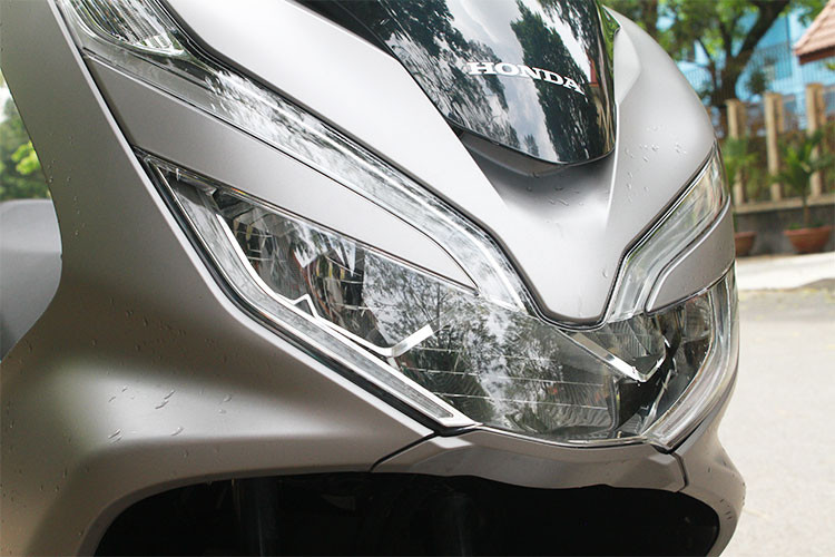 Phía trước xe ngoài kính chắn gió lớn, PCX mới còn được cải tiến hơn bằng cách tạo thêm điểm nhấn cho phần đèn trước thông qua việc sử dụng tấm ốp đặt giữa đèn pha và đèn định vị. Đồng thời vị trí của 2 đèn cũng được bố trí chếch lên phía trên, góp phần tăng thêm độ sắc sảo và cảm giác bề thế của cụm đèn, mang lại cảm giác oai hiện đại cho phần đầu xe.