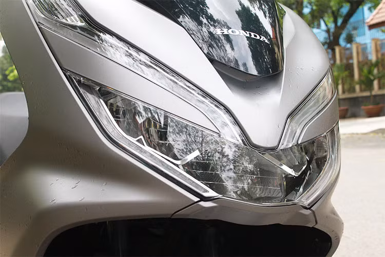 Phía trước xe ngoài kính chắn gió lớn, PCX mới còn được cải tiến hơn bằng cách tạo thêm điểm nhấn cho phần đèn trước thông qua việc sử dụng tấm ốp đặt giữa đèn pha và đèn định vị. Đồng thời vị trí của 2 đèn cũng được bố trí chếch lên phía trên, góp phần tăng thêm độ sắc sảo và cảm giác bề thế của cụm đèn, mang lại cảm giác oai hiện đại cho phần đầu xe.