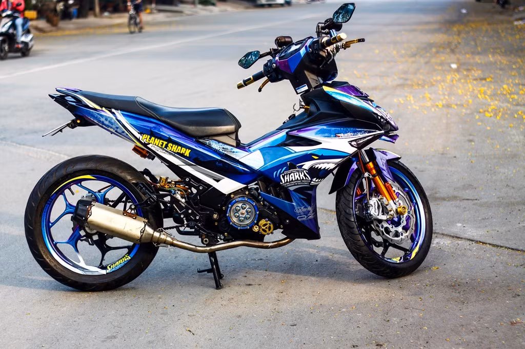 Nhờ dàn áo được sơn tem đấu hoàn toàn cùng các "đồ chơi" được chọn lọc kỹ đẹp mắt, chiếc Yamaha Exciter 150 của người chơi xe tại Trà Vinh đã trở nên ấn tượng hơn rất nhiều so với nguyên bản cũng như nhiều bản độ tem đấu dán đề can khác hiện nay.