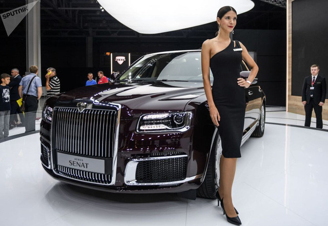 Một cô nàng người mẫu đang tạo dáng bên mẫu xe sang Aurus Senat 2019 phiên bản "dân sự" của mẫu limousine phục vụ Tổng thống Nga Vladimir Putin. Mẫu xe này có vẻ ngoài khá giống xe Rolls-Royce.