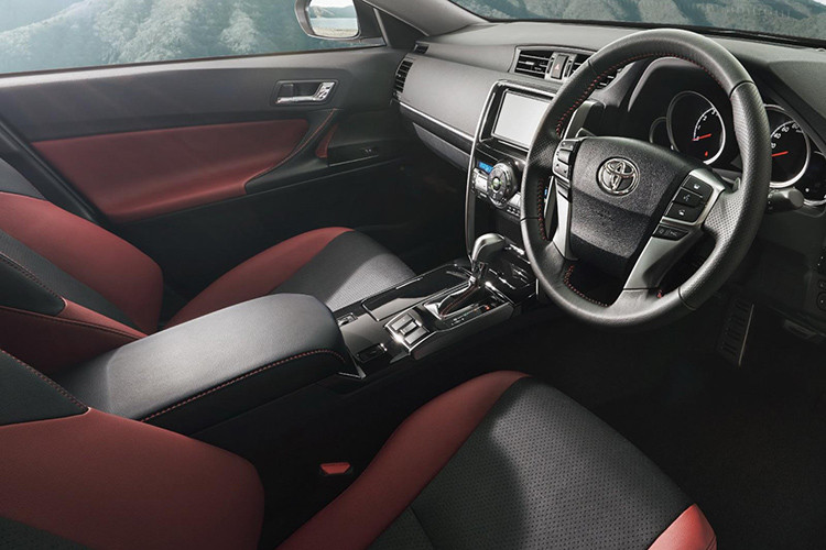 Bên trong Toyota Mark X Final Edition 2019 xuất hiện không gian nội thất phối 2 màu đen - đỏ tương phản, đậm chất thể thao. Ghế và mặt cửa của phiên bản đặc biệt này đều được bọc bằng chất liệu da tổng hợp. Trong khi đó, trên vô lăng 4 chấu, cần số, mặt cửa, ghế và bệ tì tay đều có chỉ khâu màu đỏ làm điểm nhấn.