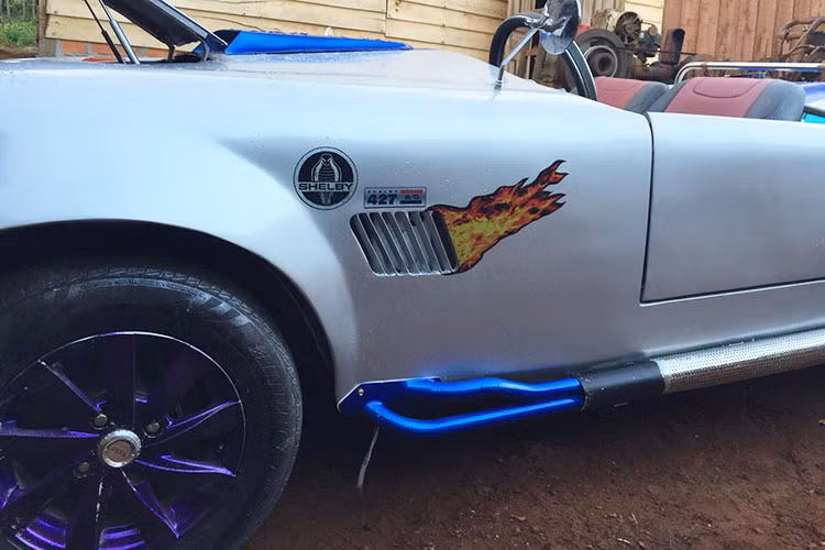 Mới đây, chủ nhân của chiếc Shelby Cobra 427 tự chế đã bắt tay "làm đẹp" cho chiếc xe của mình. So với màu sơn ban đầu đen bóng cùng 2 sọc đỏ chạy dài từ nắp capô, bộ áo mới của chiếc Shelby Cobra 427 tự chế được chủ nhân cho sơn lại màu bạc đi kèm 2 sọc cỡ lớn màu xanh dương.